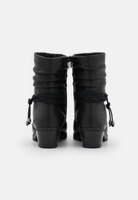 Botas de tobillo de cuero negro con un diseño arrugado, detalle de cuerda decorativa y un tacón bajo apilado. Cierre con cremallera en la parte trasera.