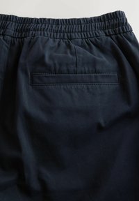 Navy-Shorts mit elastischem Bund und glatter Textur, ausgestattet mit einer einzelnen Gesäßtasche mit genähtem Rand für zusätzliche Details.