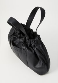 Zwarte leren tas met een gerimpelde bovenkant, twee handvatten en een voorvak. De gladde textuur en afgeronde vorm benadrukken het compacte ontwerp.