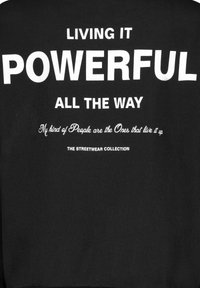Schwarzer Sweatshirt mit auffälligem weißen Text: "LIVING IT POWERFUL ALL THE WAY" mit einem kleineren Slogan darunter, alles in einer fetten Schriftart.