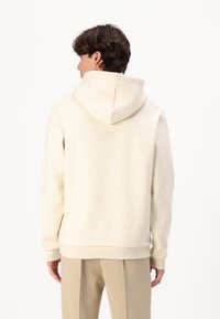 Cream-colored hoodie with a relaxed fit, adjustable drawstring hood, ribbed cuffs, and hem, made from soft cotton fabric.