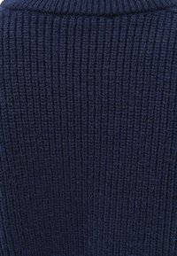 Marineblauer Strickpullover mit Rippstruktur und Rundhalsausschnitt. Der Stoff wirkt weich und mittlerem Gewicht, geeignet zum Übereinandertragen.