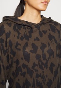 Felpa marrone con un design a stampa animale nera, realizzata in un tessuto strutturato, con una vestibilità casual e cappuccio regolabile con cordino.