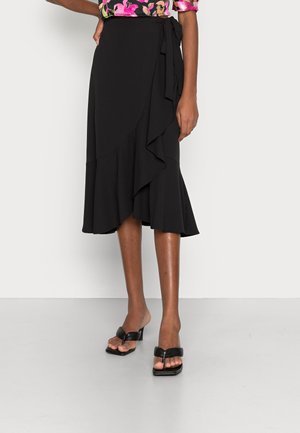 Black wrap midi skirt with ruffle detail, worn with black heeled sandals and a pink floral top.