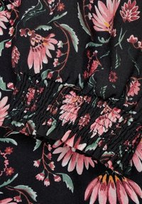 Kwiatowa tkanina z czarnym tłem i różowymi oraz zielonymi kwiatami. Tekstura jest miękka z marszczonym elastycznym wykończeniem.