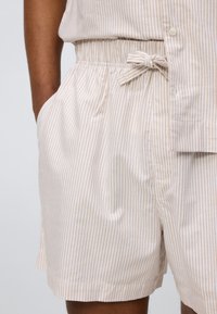 Σορτς με ρίγες κατασκευασμένα από ελαφρύ ύφασμα, με ελαστική μέση και κορδόνι, πλαϊνές τσέπες και άνετη εφαρμογή.