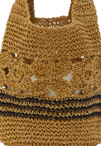 Vævet stråtaske i tan med blomster-crochet-design og sorte stribede detaljer. Åben top med robuste håndtag for nem bæring.