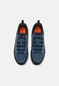 Baskets de sport bleues et noires dotées d'un matériau en maille, d'accents orange et d'une semelle texturée. Conçues avec des lacets traditionnels et un col rembourré.