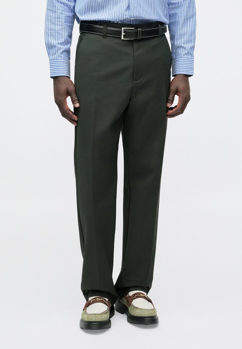 Σκούρα πράσινα παντελόνια με ίσια  κοπή και λεία υφή, που διαθέτουν μπροστινές τσέπες και μαύρη ζώνη με ασημένια αγκράφα.