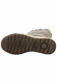 Suela de bota color beige claro con estrías para un mejor agarre, con un detalle de logotipo circular. La parte superior tiene una textura suave con un borde de pelaje sintético.