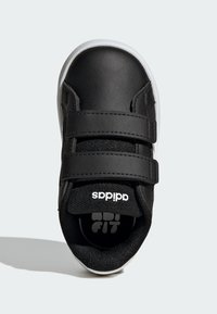 Černá teniska s vrchní částí z umělé kůže, dvěma suchými zipy, bílou podrážkou a texturovanou textilní podšívkou s logem Adidas na jazyku.