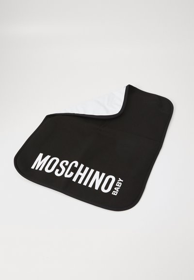 Svart och vit Moschino Baby haklapp med stor vit logotyptext, rundade hörn och mjukt tyg mot en enfärgad bakgrund.