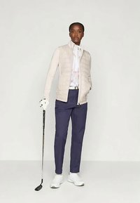 Svetlo bež prešita jakna, bela srajca s ovratnikom, temno modre hlače, bele čevlje, drži golf palico, sodoben dizajn z gladkimi teksturami.