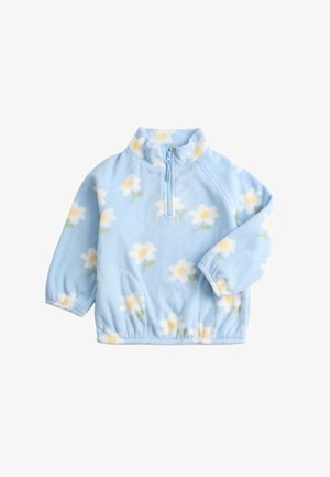 Pile azzurro chiaro con motivo floreale composto da fiori bianchi e gialli. Ha un colletto a mezza zip e polsini bianchi a coste.