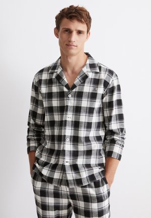 Svart och vit rutmönstrad pyjamas i mjukt tyg, med en knapp-up skjorta med notch-krage och matchande byxor med elastisk midja.