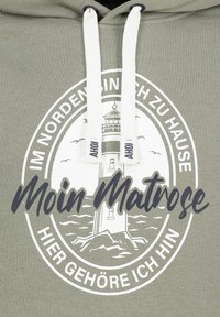 Olijfgroene hoodie met witte trekkoorden en een centraal grafisch ontwerp van een vuurtoren, met tekst elementen in een zwart-wit cirkelontwerp.