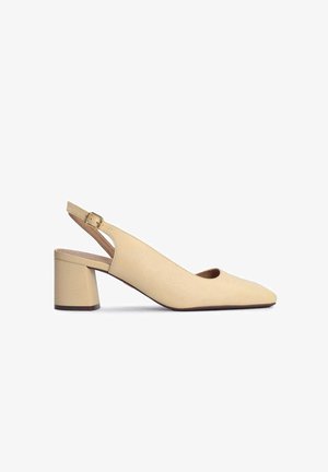 Chaussure slingback en cuir beige avec un bout pointu et un talon bloc de hauteur moyenne. Comprend une bride à boucle et un détail découpé au niveau du talon.