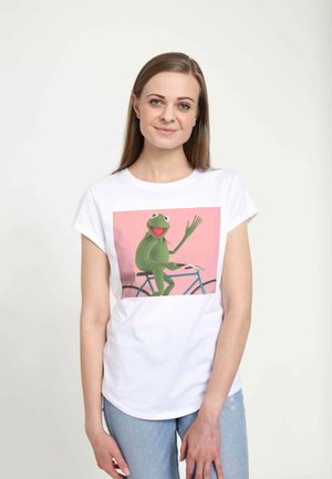 T-shirt en coton blanc avec un motif imprimé rose représentant une grenouille verte sur un vélo bleu, avec un bras levé et un large sourire.