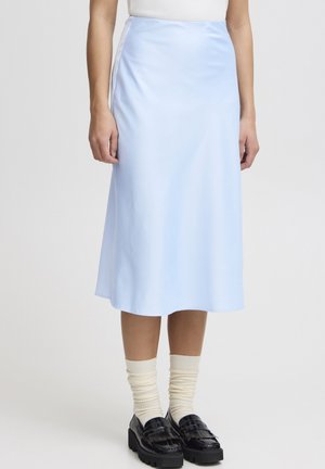 Hellblauer Satin-Midi-Rock mit glatter Textur, der eine ausgestellte Silhouette aufweist und seitliche Nahtdetails hat, kombiniert mit dunklen Loafers und crèmefarbenen Socken.