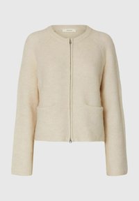 Cardigan en tricot de couleur crème avec fermeture éclair à l'avant et deux poches avant, doté de manches longues et d'un col rond.