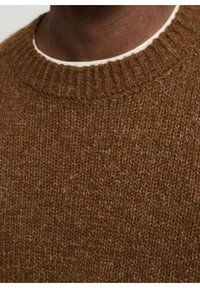 Ruskea neulepaita, jossa on ribattu pyöreä kaula-aukko, pehmeä ja tekstuuri, sekä lähikuva kudontasyystä.