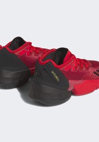 Zapatillas de baloncesto rojas con acentos negros, que cuentan con una parte superior de malla, suela gruesa y una marca prominente. Los cordones complementan el diseño vibrante.