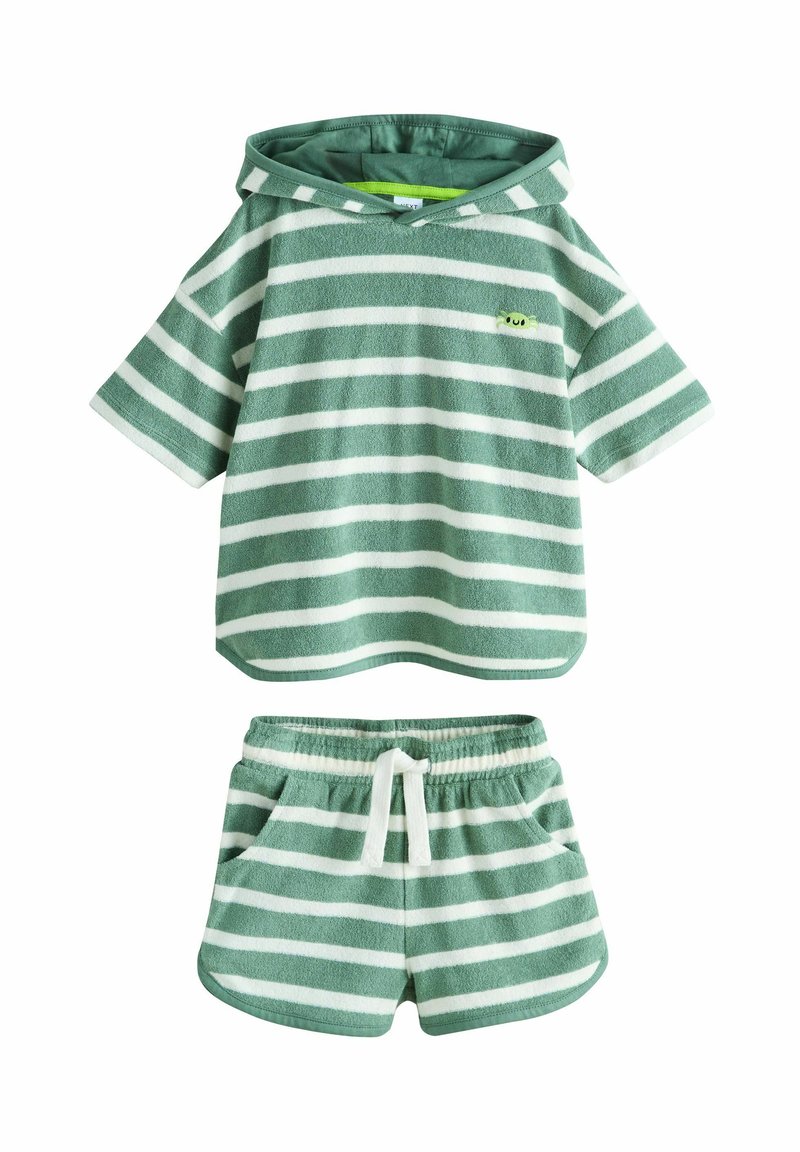 Zöld-fehér csíkozású kapucnis polár felső, hozzá illő rövidnadrággal párosítva. Puha textúrájú, húzózsinóros derékpánttal és két oldalzsebbel rendelkezik.