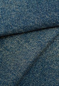 Denimstoff in Dunkelblau mit einer Textur aus dicht gewobenen Fäden, die eine subtile Variation der Farbtöne und sichtbare Nähdetails aufweist.