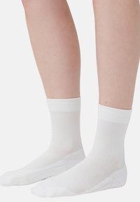Witte enkelsokken met ribbelmanchetten, gemaakt van een gladde, rekbare stof. Het ontwerp heeft een naadloze teen en een ademende meshtextuur.
