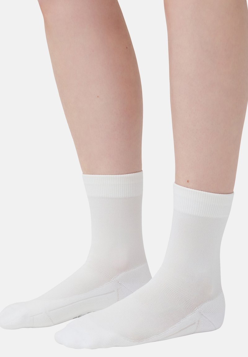 Witte enkelsokken met ribbelmanchetten, gemaakt van een gladde, rekbare stof. Het ontwerp heeft een naadloze teen en een ademende meshtextuur.