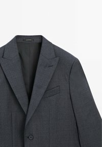 Dunkelgrauer maßgeschneiderter Blazer mit einem Ein-Knopf-Verschluss, Reverskragen und einer Brusttasche mit einer strukturierten Stoffoberfläche.