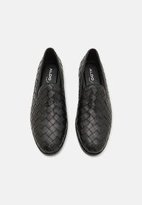Black woven leather slip-on shoes with a smooth toe design and a low profile. Interior displays the brand name "ALDO." Textured surface detail.