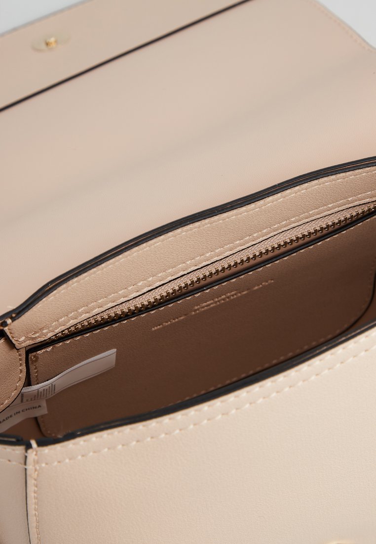 Sac en simili cuir beige avec un extérieur lisse, des finitions noires, une fermeture éclair et un seul compartiment visible à l'intérieur.