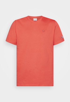 Korallrød t-shirt med korte ærmer og rund halsudskæring med lille Champion-logo på brystet og ærmet på hvid baggrund.