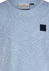 Jasnoniebieska koszulka z delikatnym, całkowitym wzorem tekstu oraz czarną metką marki po lewej stronie klatki piersiowej.