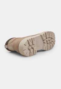 Încălțăminte bej cu o talpă din cauciuc solidă, având un model texturat de aderență și accente din material textil, proiectată pentru durabilitate și tracțiune.