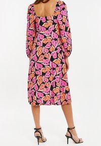 Kwiatowa sukienka midi z bufkami, w wielokolorowy wzór liści w odcieniach różu i pomarańczy na czarnym tle. Kwadratowe plecy, gładka tekstura.