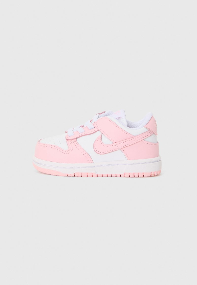 Nike-tennarit, joissa on valkoinen nahkapinta ja vaaleanpunaisia yksityiskohtia, pyöreä kärki, nauhakierre ja paksu, karheapintainen kumipohja.