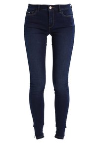 Jeans ajustados azules de denim, con una cintura alta, cierre de cremallera y un lavado oscuro con sutiles detalles de costura. Ajustados a lo largo de la pierna.