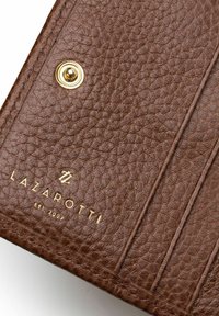 Portafoglio in pelle marrone con superficie texturizzata, dotato di hardware dorato e logo impresso. Include slot per carte e chiusura a scatto.
