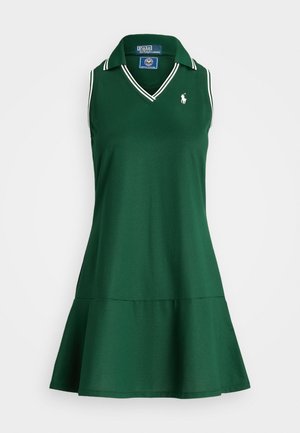 Ärmelloses grünes Polokleid mit weißer Einfassung am Kragen und an den Armlöchern, V-Ausschnitt, ausgestelltem Rock und kleinem weißen gesticktem Logo auf der Brust.