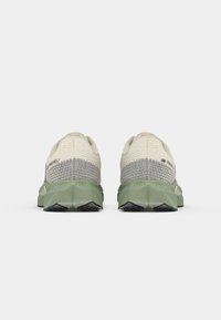 Hellebeige Sportschuhe mit strukturiertem Obermaterial und grauen Akzenten. Merkmale eine klobige grüne Sohle mit einem gemusterten schwarzen Profil.