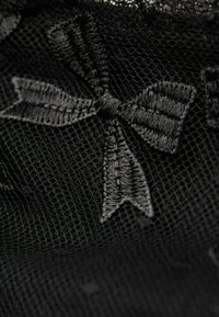 Black lace fabric featuring an intricate embroidered bow design, showcasing a mesh texture with fine detailing.