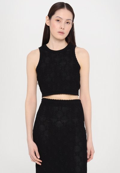 Fekete kötött crop top, texturált virágmintákkal, kerek nyakkivágással és hullámos széllel. Tökéletesen passzol a matching fekete szoknyához.