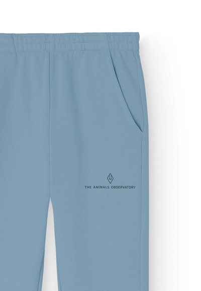 Hellblaue Sweatpants mit einem Kordelzugbund, Seitentaschen und einem dezenten Logo auf dem linken Oberschenkel. Hergestellt aus weichem Material.