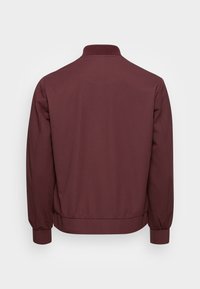 Chaqueta bomber burdeos con cuello, puños y cintura acanalados, mostrada desde atrás sobre un fondo claro liso.