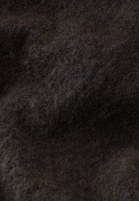 Tessuto di lana morbido e strutturato in un profondo colore marrone, caratterizzato da una superficie pelosa con fibre naturali e sottili variazioni tonali.