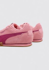 Zapatillas Puma rosas con materiales de ante y sintéticos, con una franja rosa más oscura, superficie texturizada y suela de goma con detalle de corcho.