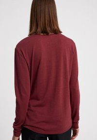 Langarmshirt in bordeauxrood, gemaakt van zachte stof met een relaxte pasvorm. Heeft een ronde halslijn en verlaagde schoudernaden.