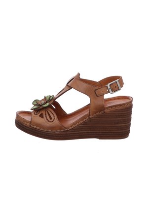Brown leather wedge sandal featuring a floral accent, open toe, adjustable strap, and textured wedge sole. Detailed cutouts on the upper.